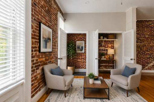A living room with a brick wall and two chairs.