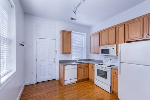 A kitchen with white appliances and wooden cabinets.
