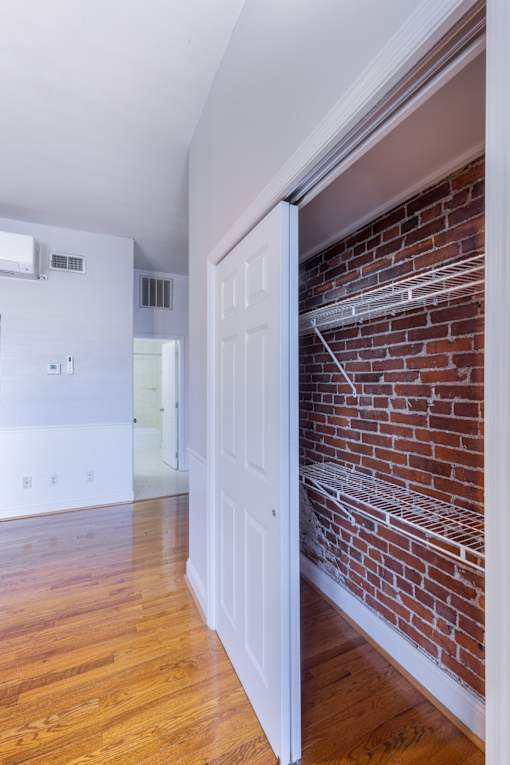 A white door is open to a room with a brick wall.