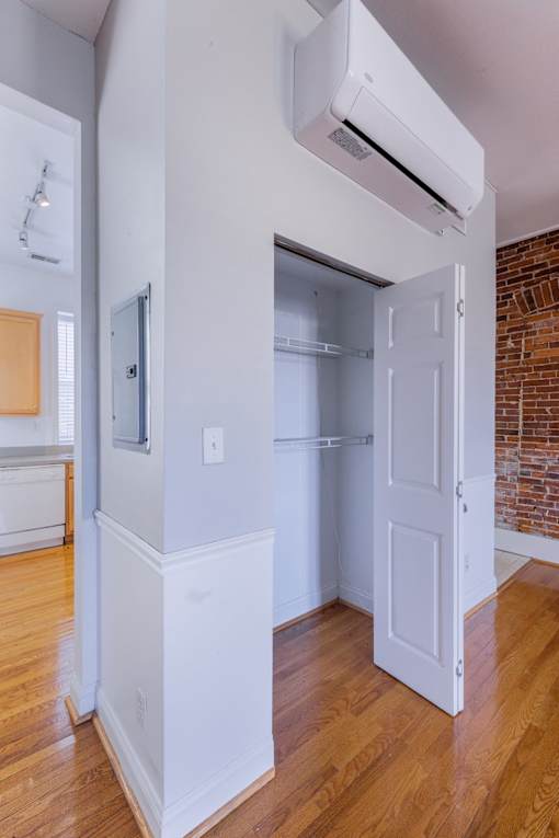 A white door is open to a small room with a brick wall.