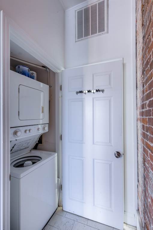 A white door is open to a small kitchen with a washer and dryer.