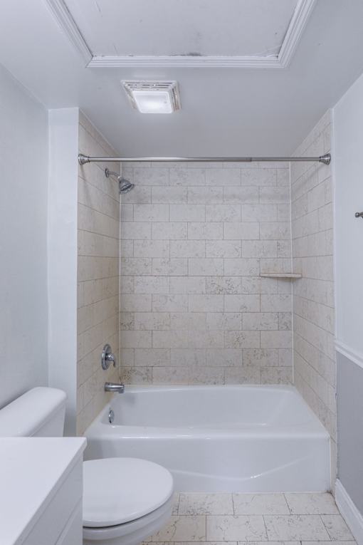 A white bathroom with a toilet, tub, and shower.