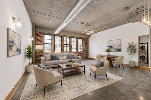 A living room with a grey sofa, a grey armchair, a wooden coffee table, and a rug.