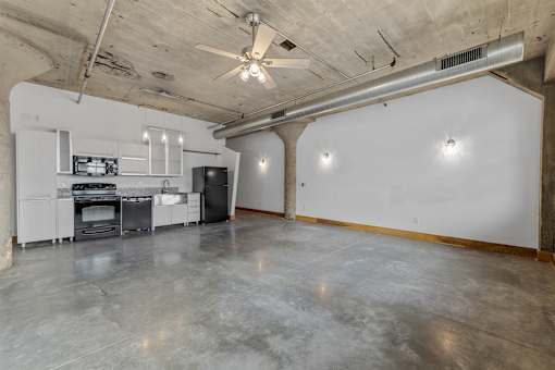 A spacious garage with a concrete floor and a ceiling fan.