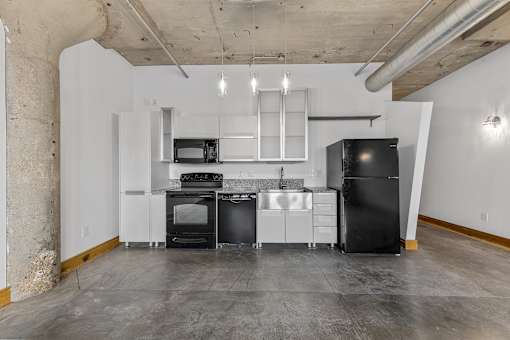 A kitchen with black appliances and white cabinetry.