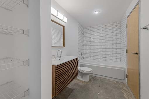 A white tiled bathroom with a toilet, sink, and bathtub.