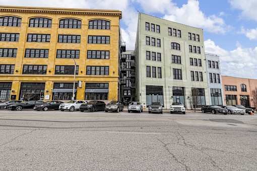 A parking lot with cars and two buildings.