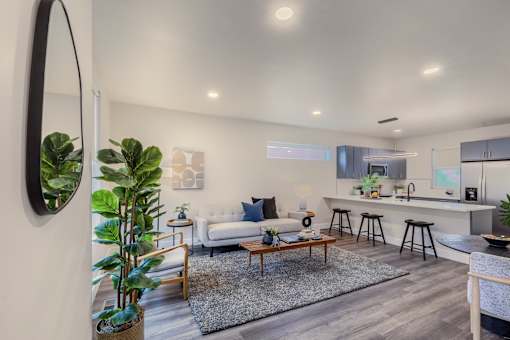 A modern living room with a white couch, a coffee table, and a large mirror on the wall.