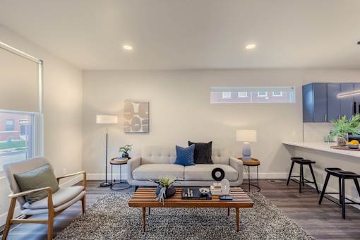 A living room with a white couch, a wooden coffee table, and a grey rug.