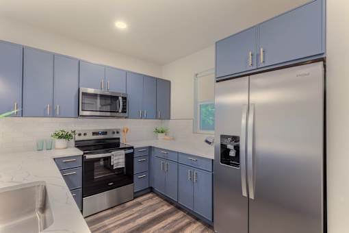 A kitchen with blue cabinets and stainless steel appliances.
