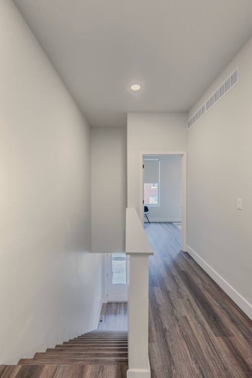 A hallway with wood flooring and white walls.