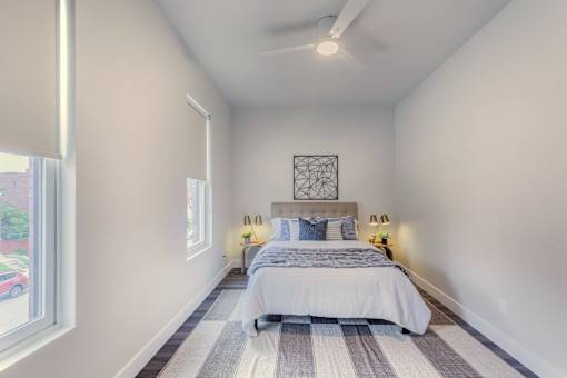A bedroom with a bed, pillows, and a ceiling fan.