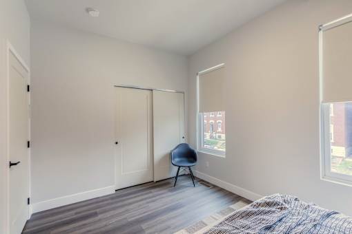 A room with a bed, chair, and sliding doors.