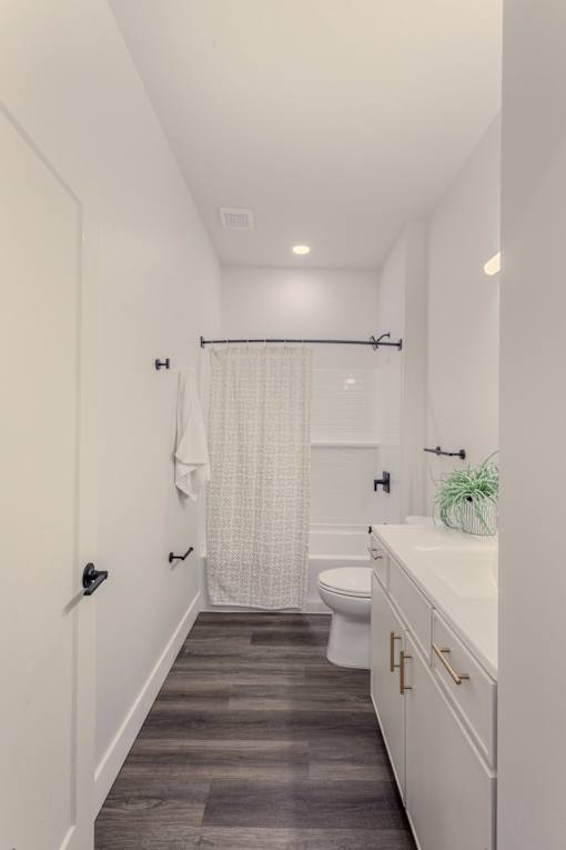 A white bathroom with a toilet, sink, and shower curtain.