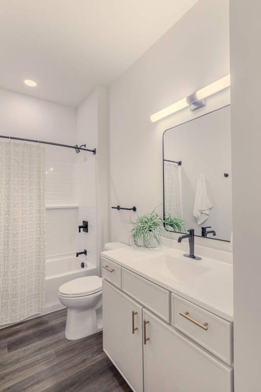 A white bathroom with a toilet, sink, and a mirror.