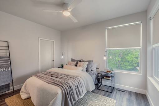 A bedroom with a large bed and a window with blinds.
