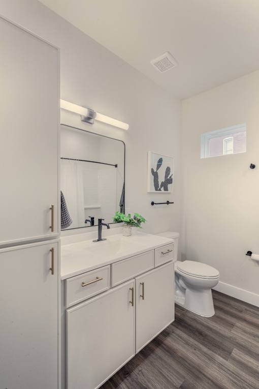 A white bathroom with a toilet, sink, and mirror.