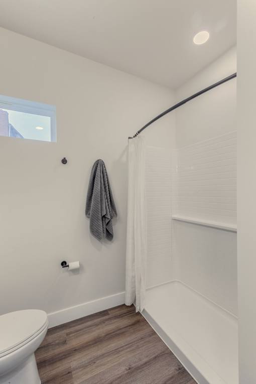 A white toilet sits in a bathroom with a grey towel hanging on the wall.