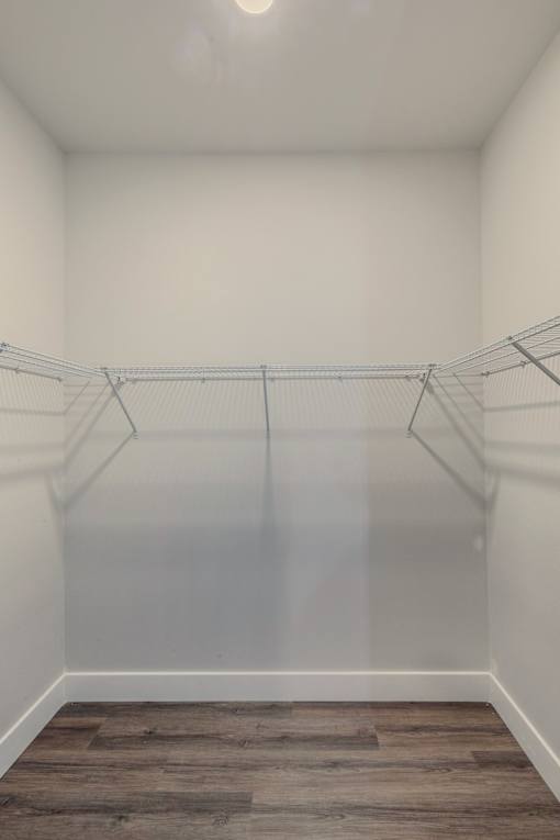 A room with a grey floor and white walls with clothes hangers.