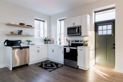 A kitchen with white cabinets and a black and white rug on the floor.