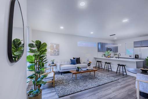 A modern living room with a white couch, a coffee table, and a large mirror on the wall.