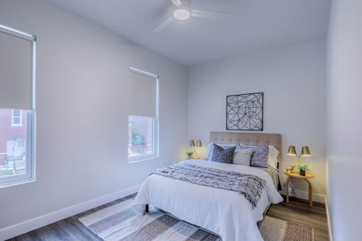 A bedroom with a large bed and a window with blinds.