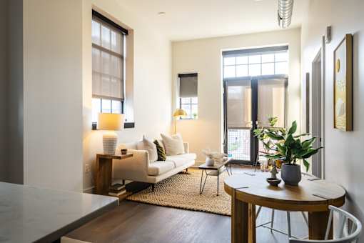 A modern living room with a white sofa, a wooden coffee table, and a rug on the floor.
