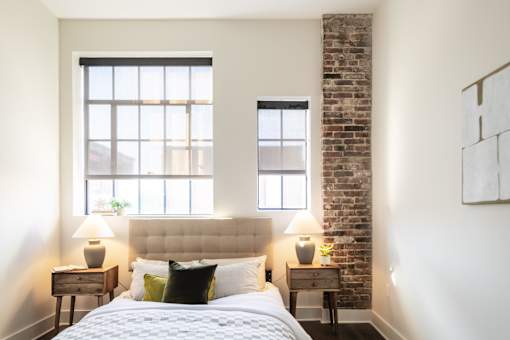 A bedroom with a brick wall and a large bed.
