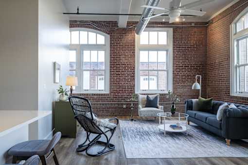 A living room with a black rocking chair and a grey sofa.