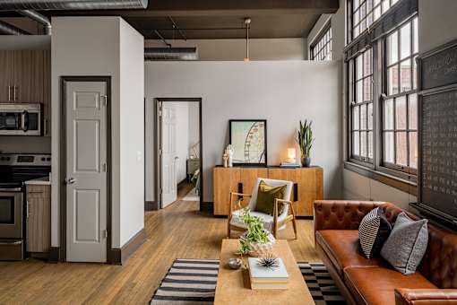 A brown leather couch sits in a living room with a wooden coffee table in front of it.