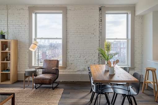 A white brick wall with a table and chairs in front of it.