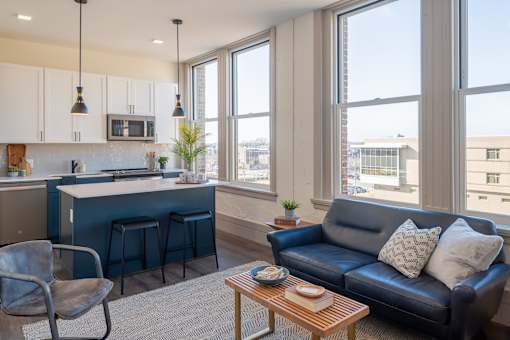 A modern kitchen with a blue couch and a grey chair.