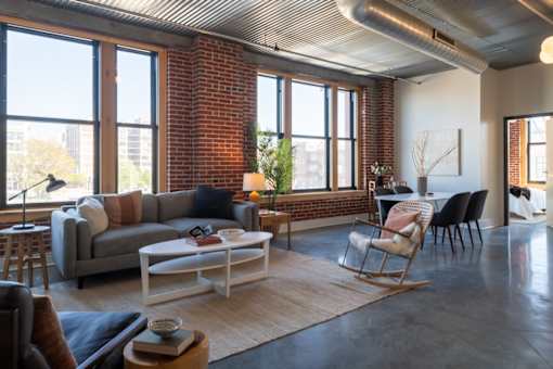 A living room with a grey couch, a white coffee table, and a wooden rocking chair.