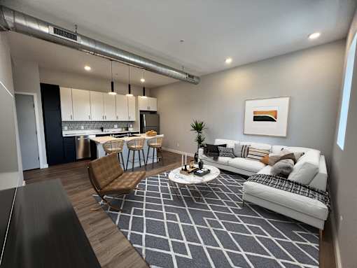 A modern living room with a kitchen in the background.