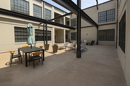 A patio with a table and chairs is surrounded by a building.
