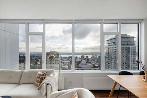 A modern living room with a view of the cityscape outside the large window.