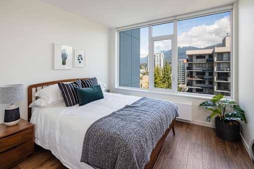 A bedroom with a large bed and a view of the city.