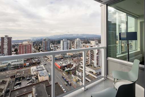 A balcony with a chair overlooking a cityscape.