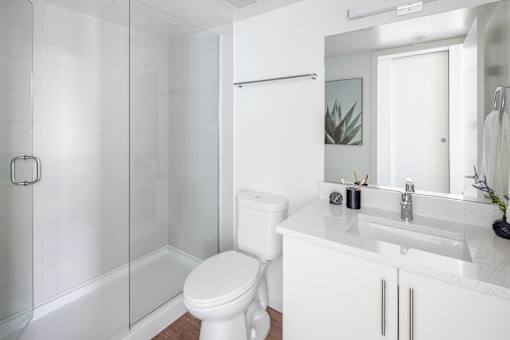 A white bathroom with a toilet, sink, and shower.