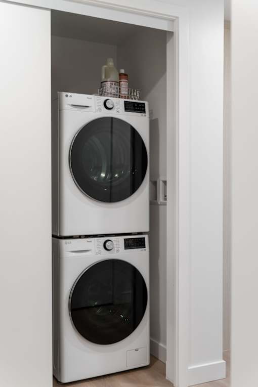 Two white front loading washing machines in a small laundry room.