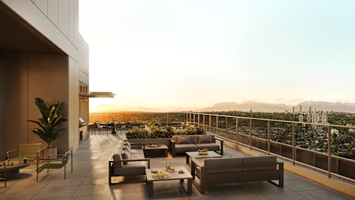A rooftop patio with couches and a table with a view of the city.