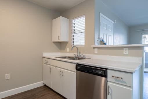 a kitchen with white cabinets and a stainless steel dishwasher