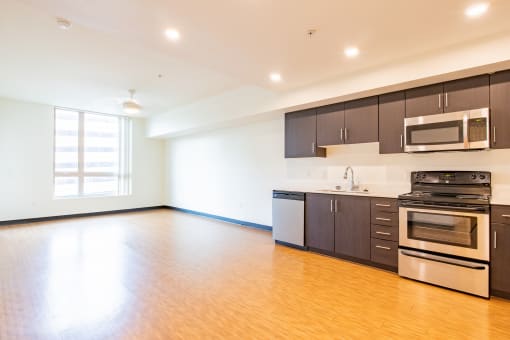 an empty kitchen with wood flooring and stainless steel appliances