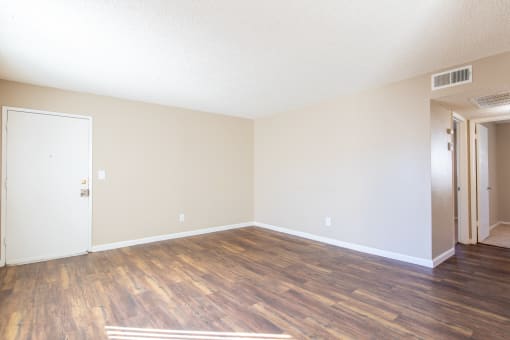 an empty living room with a hard wood floor and white walls