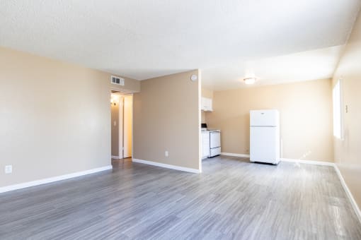 an empty living room and kitchen with a refrigerator and