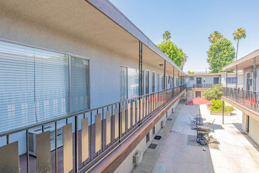 a long balcony with tables and chairs at a building with windows