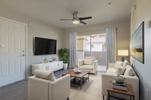 a living room with white furniture and a ceiling fan