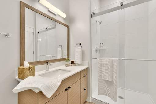 A bathroom with a sink, mirror, and shower.
