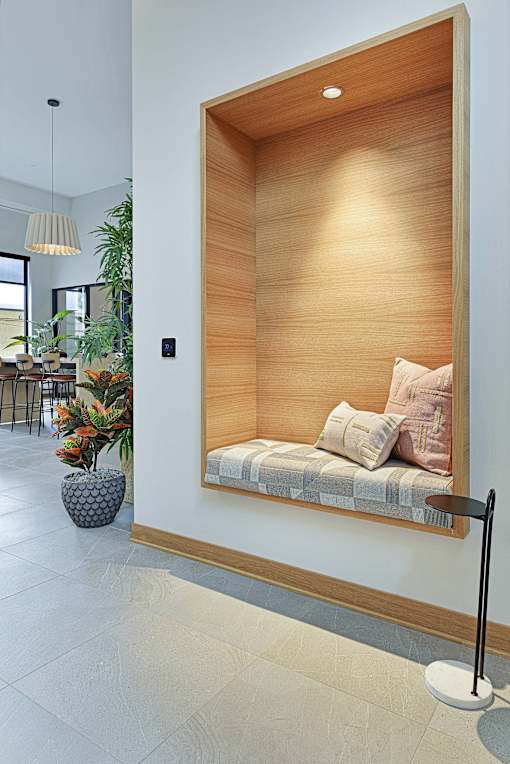 A modern room with a wooden panelled wall and a bench with cushions.