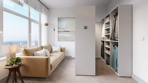 A room with a tan couch, a wooden table, and a large window overlooking the city.